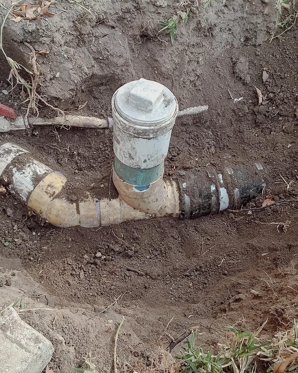 Cracked, stained sewer cleanout fittings in the dirt
